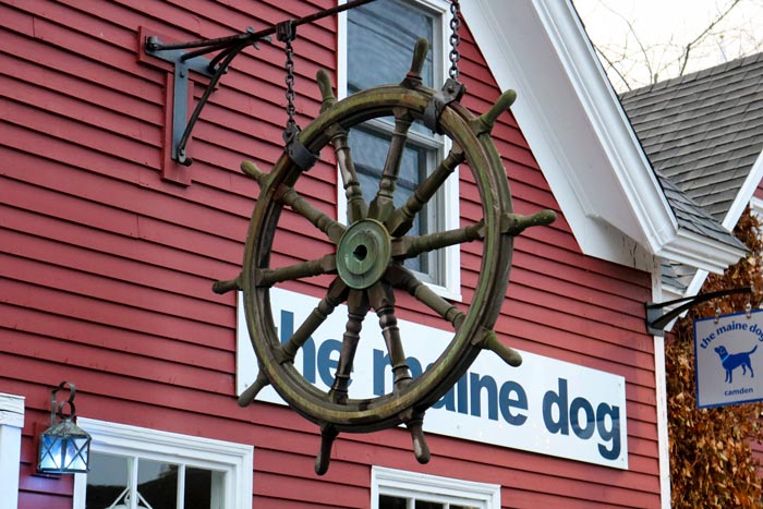 A Ship's Wheel Outside The Maine Dog
